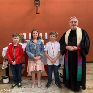 Adrain Franke, Sophie Schwarz und Joshua Becker mit Pfarrer Stolz nach ihrer Einsegnung beim Kirchweihgottesdienst in der evangelischen Johanneskirche